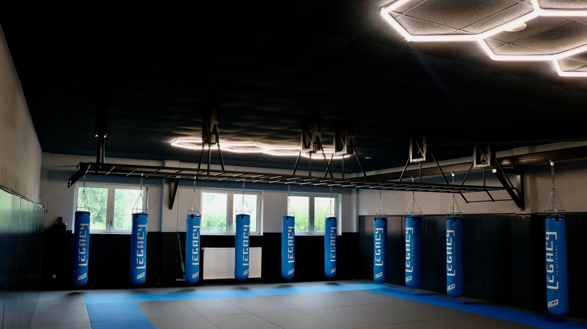 Blick über die Mattenfläche der Grappling-Halle mit Sandsackreihe und Fenstern in Pinneberg